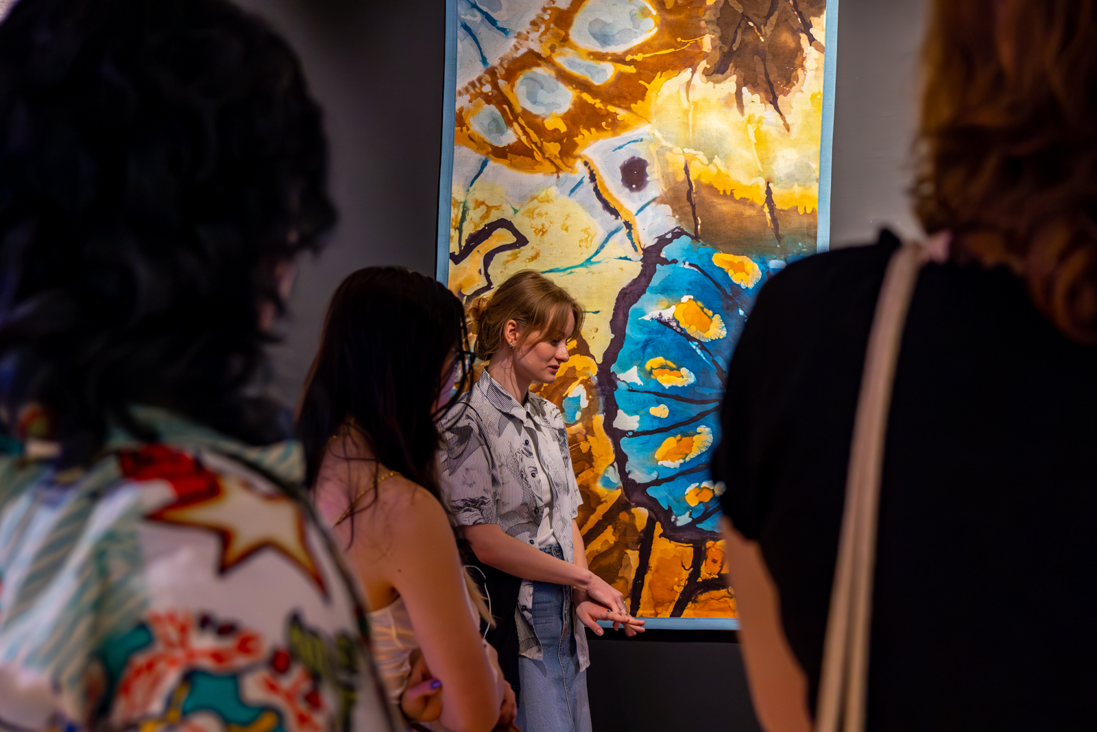 Grupa kobiet stojąca przy obrazie o tematyce abstrakcyjnej.