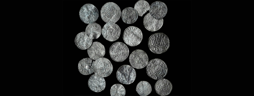 Dwadzieścia trzy srebrne monety pokryte wybitymi napisami oraz symbolami.