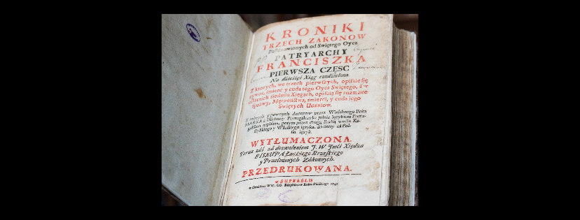 Osiemnastowieczna księga (Kroniki Trzech Zakonów), otwarta na stronie zadrukowanej czarnymi i czerwonymi literami.