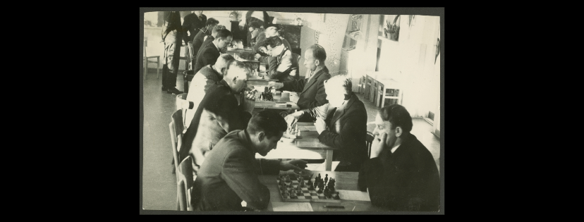 Czarnobiała fotografia przedstawiająca grupę mężczyzn rozgrywających turniej szachowy w Powiatowym Komitecie Kultury Fizycznej i Turystyki w Mońkach.